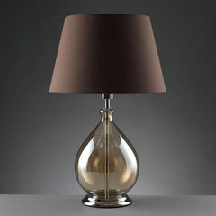 Amber glass table lamp with a dark fabric shade, displayed against a plain grey background.