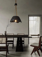 Dining room with a dark pendant light hanging above a wooden table.