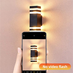 Hand holding a smartphone taking a photo of a wall-mounted light fixture with 'No video flash' text.