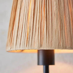 Close-up of a lamp with a textured beige shade and black base.