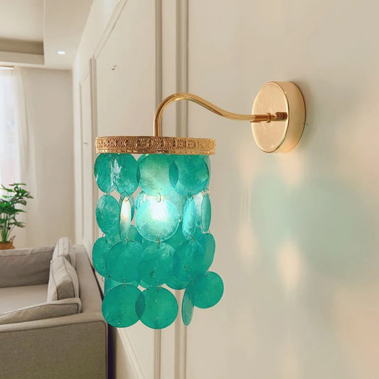 Gold wall sconce with cascading blue-green shell accents mounted on a white wall.
