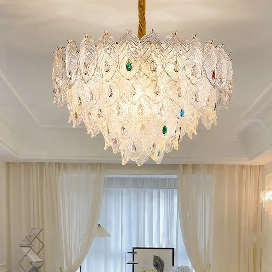 A tiered chandelier with clear crystal leaf accents and colorful gem details, suspended from a gold cord.
