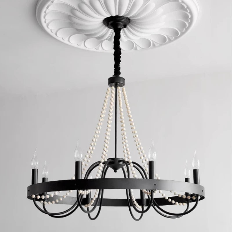 Black chandelier with pearl-like beads against a white ceiling