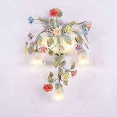 Close-up of the gold floral wall sconce, showing the intricate ceramic rose buds and leafy details.