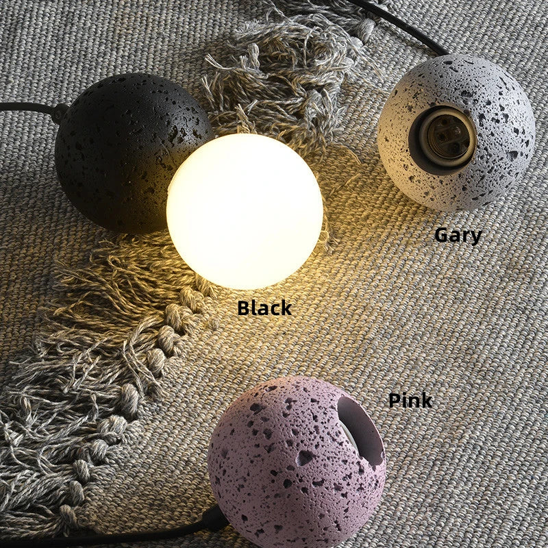 String lights with black, pink, and gray lampshades on a textured surface.