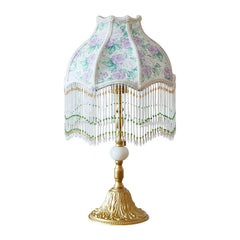 Decorative lamp with floral patterned shade and gold base on a white background