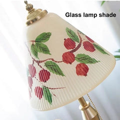 Glass lamp shade with red fruit and green leaves design on a white background