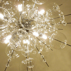 Chandelier with clear glass bubbles and metal rods against a beige background