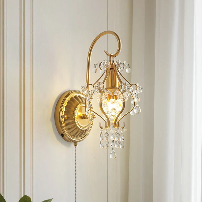 Gold wall sconce with crystal accents on a white wall