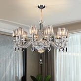 A crystal chandelier with candle-style arms and faceted crystal shades, illuminated and hanging from a ceiling.