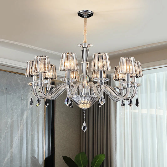 A crystal chandelier with candle-style arms and faceted crystal shades, illuminated and hanging from a ceiling.