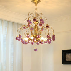 Gold chandelier with cascading purple teardrop glass pendants installed in a well-lit room