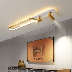 Gold linear ceiling lamp with an oval accent and two adjustable spotlights mounted on a ceiling above a piece of art.