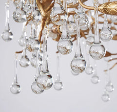 Close-up of a crystal chandelier with clear glass droplets on a light gray background.