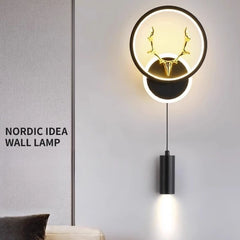 Black wall sconce with circular LED halo and integrated antler design, with a hanging downlight cylinder, text overlay 'NORDIC IDEA WALL LAMP'.