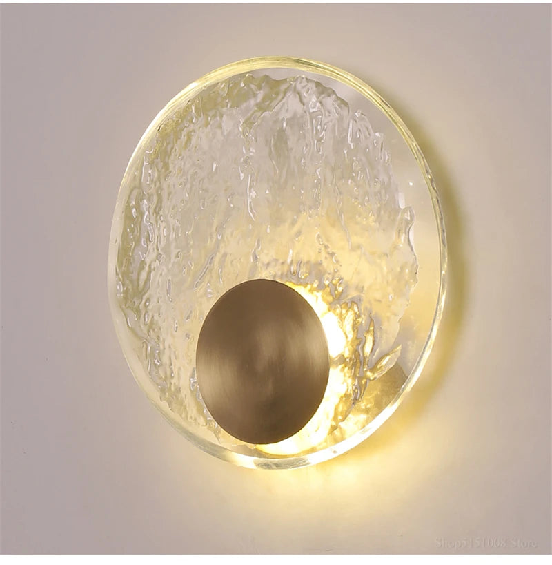 Wall-mounted light fixture with gold frame and glass cover on a neutral background