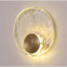 Wall-mounted light fixture with gold frame and glass cover on a neutral background