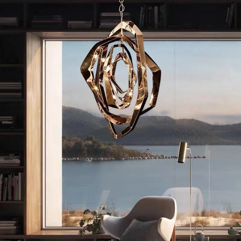 A rose gold geometric crystal pendant light suspended in front of a large window overlooking a body of water.