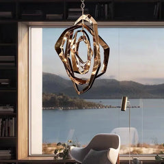 A rose gold geometric crystal pendant light suspended in front of a large window overlooking a body of water.