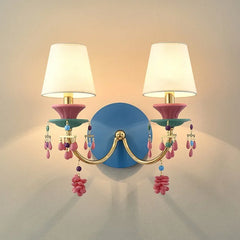 Gold wall sconce with white fabric shades and colorful beaded and flower-like accents, mounted on a blue backing plate.