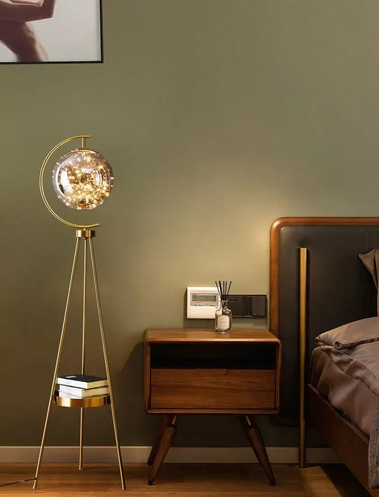 Modern bedroom with a gold floor lamp and wooden nightstand against a green wall.