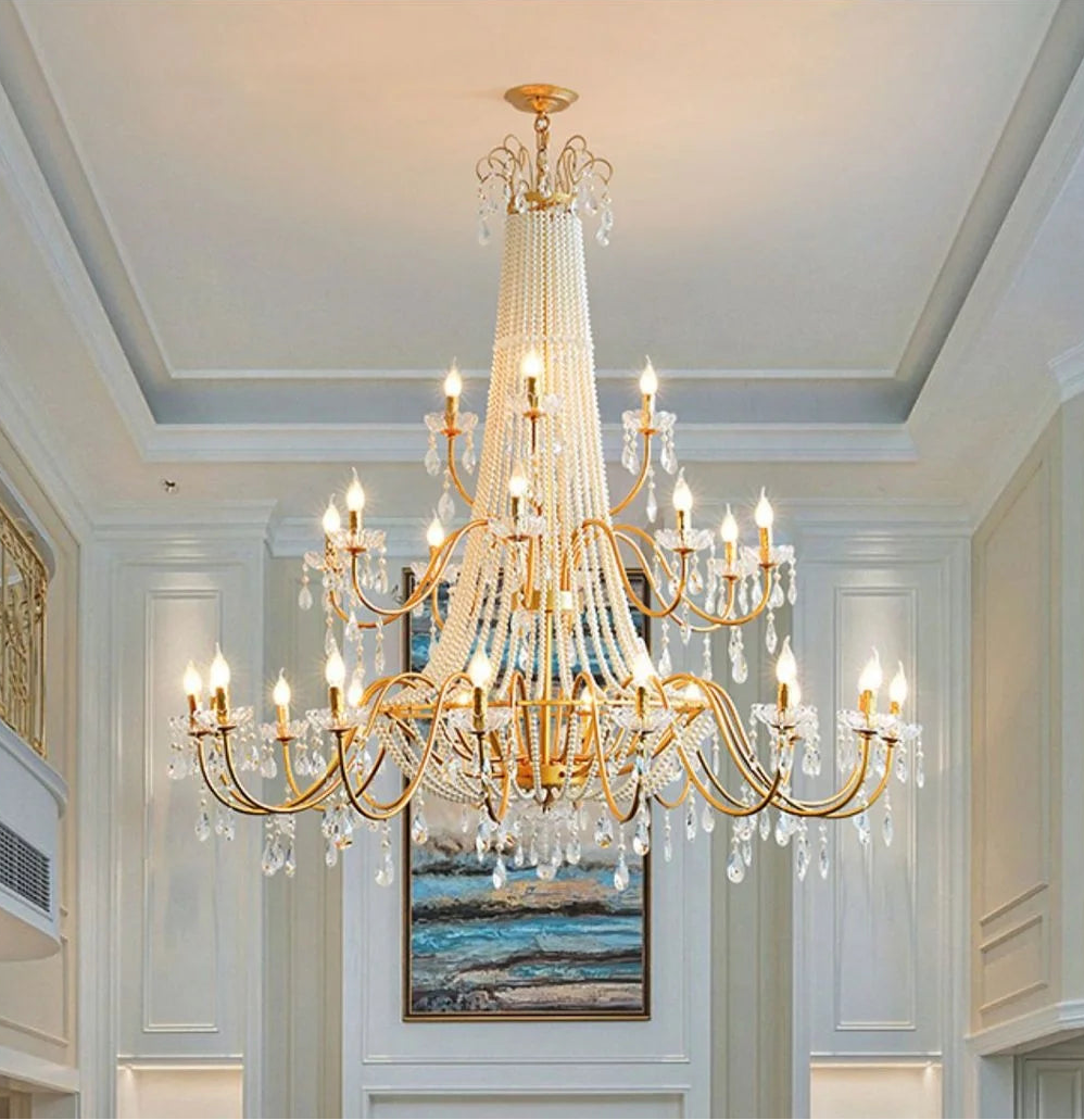 Luxurious chandelier hanging in a room with white walls and a painting on the wall.