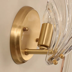 Close-up of a gold wall-mounted light fixture with clear glass shade.