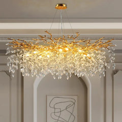 Chandelier with gold branch design and crystal accents in a room with white walls and abstract art.