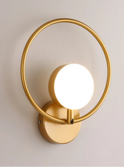 Gold wall lamp with a circular design on a light gray background