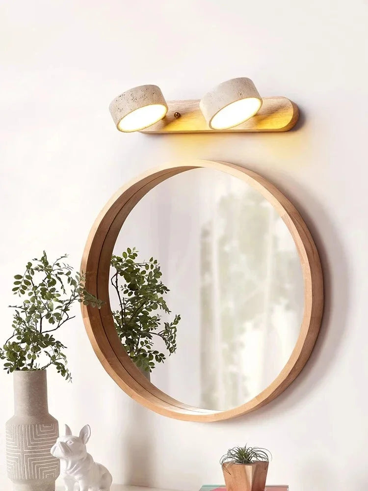 Round wooden mirror with a light fixture above it on a white wall.