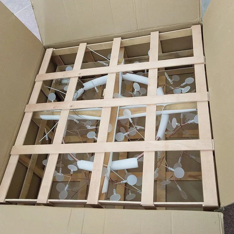 Wooden frame with white branches inside an open cardboard box