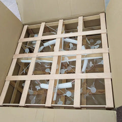 Wooden frame with white branches inside an open cardboard box
