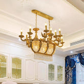 A large, ornate gold chandelier with multiple candle-style lights and cascading crystal prisms hangs from a white ceiling.