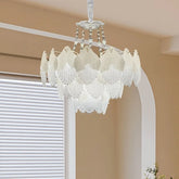 White glass leaf tiered chandelier hanging in a room with natural light