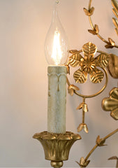 Decorative wall sconce with a light bulb inside, featuring gold and green colors.