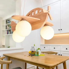 Wooden airplane pendant light with milk white glass shades illuminating a wooden dining table and chairs.