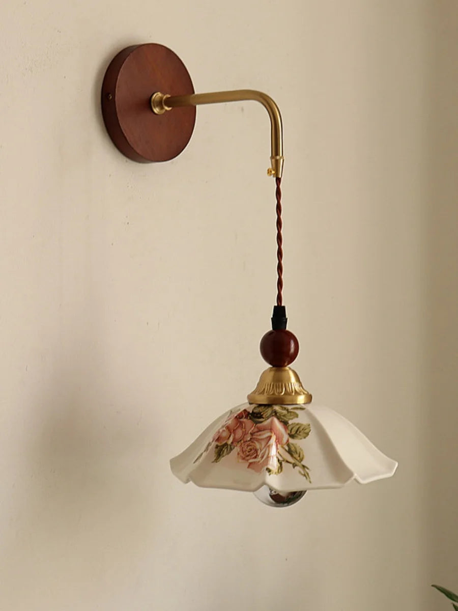 Wall-mounted lamp with floral glass shade on a beige wall