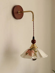 Wall-mounted lamp with floral glass shade on a beige wall