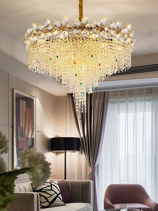 A luxurious gold chandelier adorned with cascading clear and colorful crystals, featuring petal-shaped accents, illuminating a living room.
