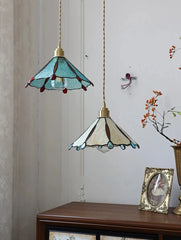 Two hanging pendant lights with stained glass shades on a wooden surface.