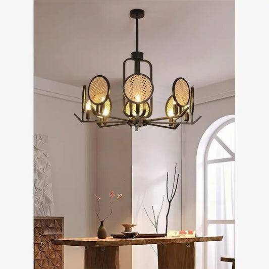 Chandelier with black metal frame and round woven rattan discs hanging over a wooden dining table.