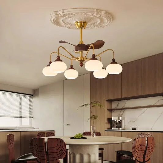 A gold sputnik starburst ceiling fan chandelier with wooden blades and frosted glass globe lights, mounted on a decorative ceiling medallion in a dining room.