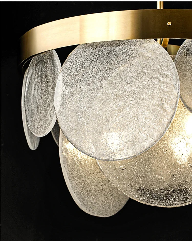 Detailed view of the textured glass discs and brushed gold frame of a modern pendant light.