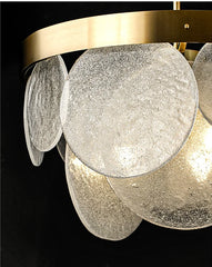 Detailed view of the textured glass discs and brushed gold frame of a modern pendant light.