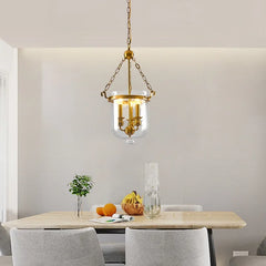Polished copper and clear glass drum pendant light installed over a dining table