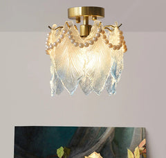 Decorative ceiling light fixture with pearl-like beads and glass elements on a gray background.