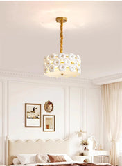 Modern chandelier hanging in a bedroom with white walls and decor.