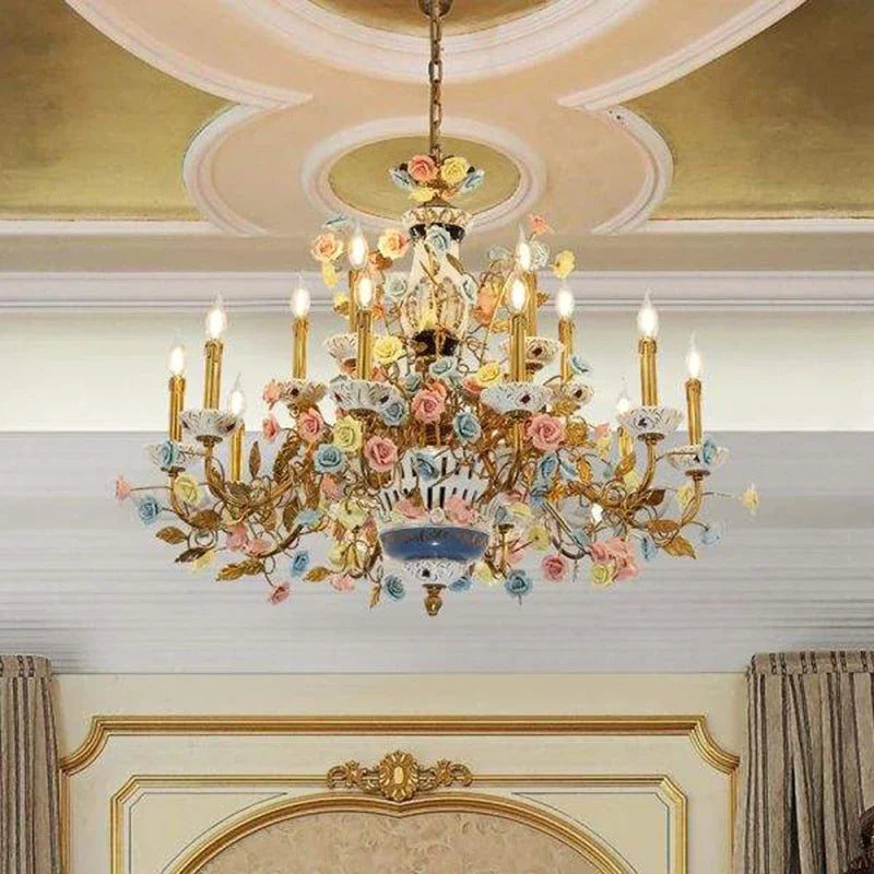 The gold ceramic rose floral chandelier installed in an opulent room with a decorative ceiling, casting a warm glow.