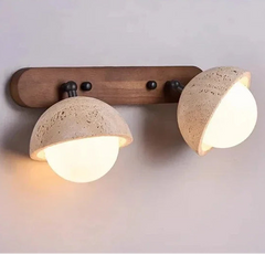 Wall-mounted light fixture with two round concrete lampshades on a plain background