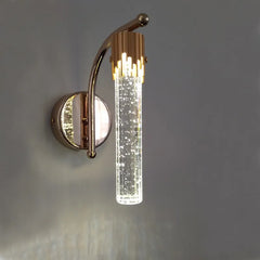 Wall-mounted light fixture with gold finish and clear glass on a gray background